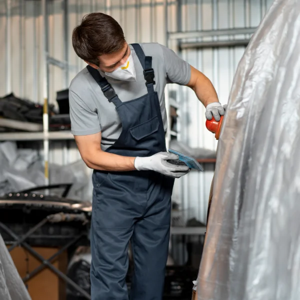 Un homme en salopette travaille sur une voiture.