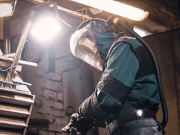 Un homme en combinaison de protection soude quelque chose.