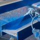 une personne pulvérisant de la peinture bleue sur une poutre métallique