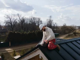 Un homme travaille sur un toit, utilisant des outils pour effectuer des réparations ou des installations.