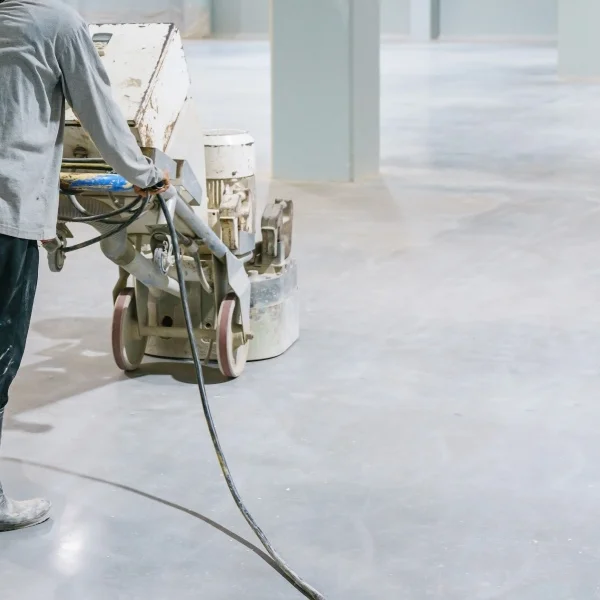 Un homme utilise une machine pour nettoyer un sol en béton.