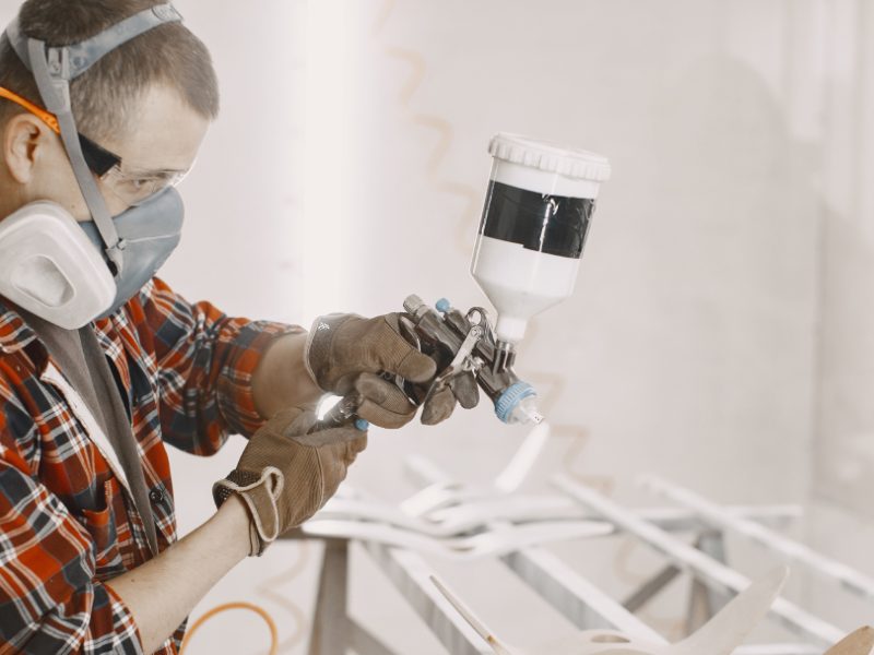 Technicien appliquant une peinture industrielle au pistolet pour assurer une performance durable et une protection optimale des surfaces